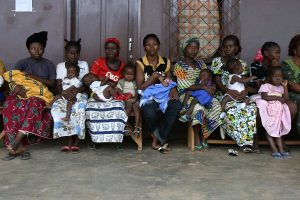 women holding children outside poliovirus vaccination clinic in Africa