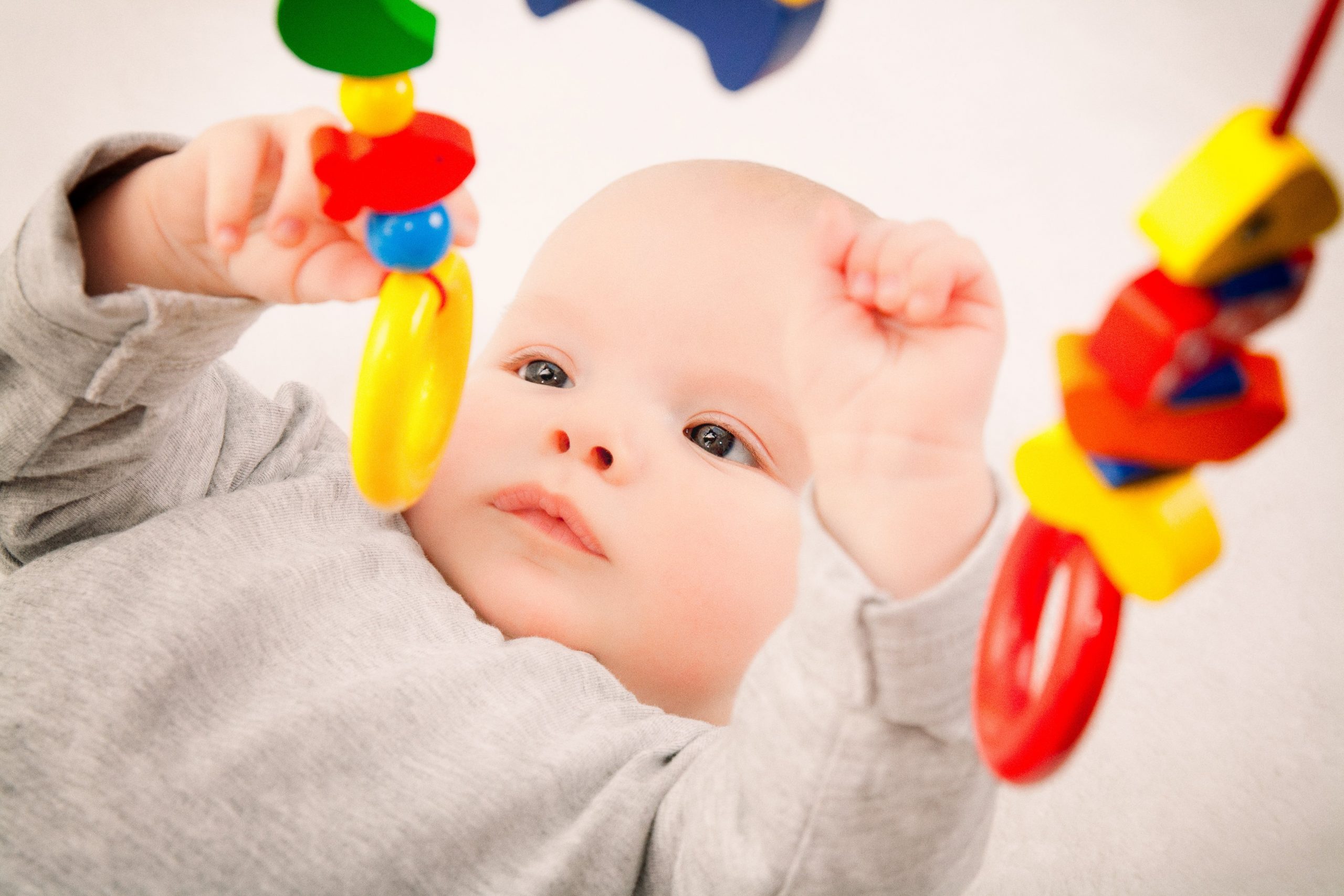 Baby learns. Ребенок с игрушкой в руках. Первые игрушки малыша. Младенец с погремушкой. Ребенок раннего возраста с погремушкой.