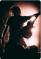 Dark image of a man playing a guitar on stage.