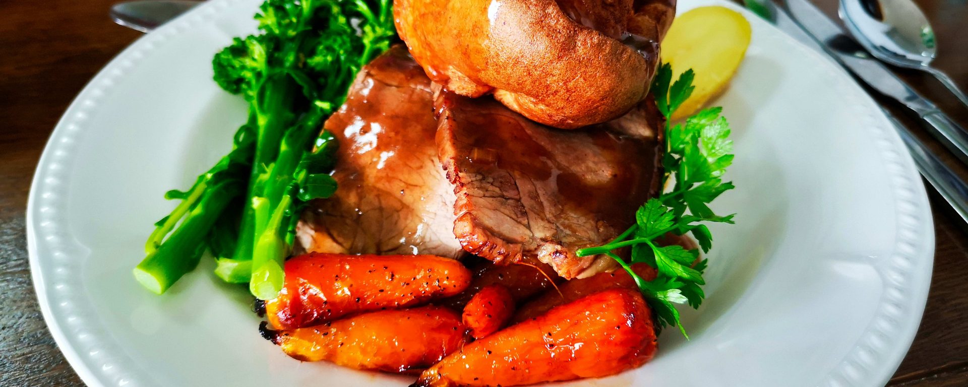 A Sunday roast with carrots, Yorkshire pudding, broccoli and gravy