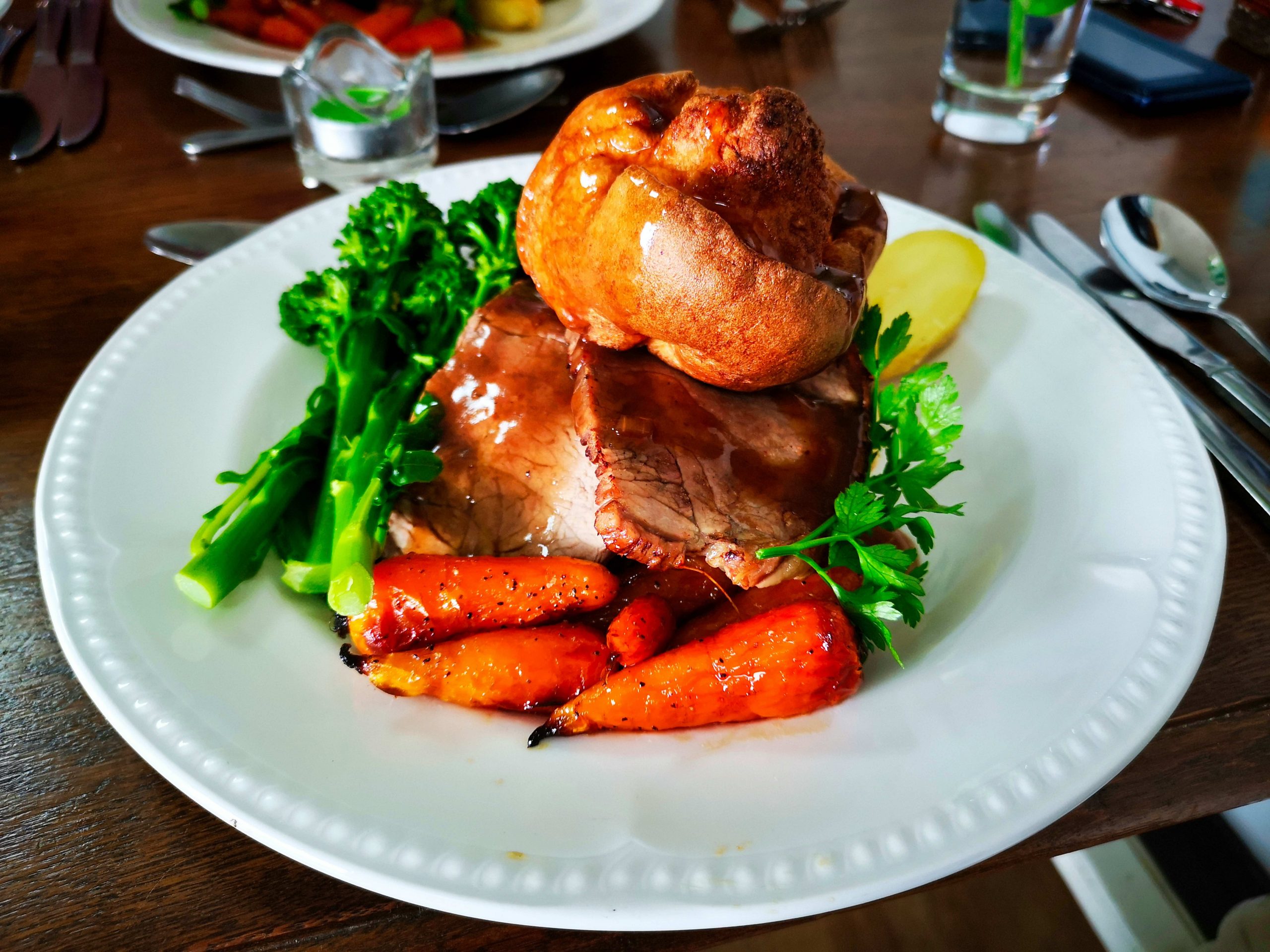 A Sunday roast with carrots, Yorkshire pudding, broccoli and gravy