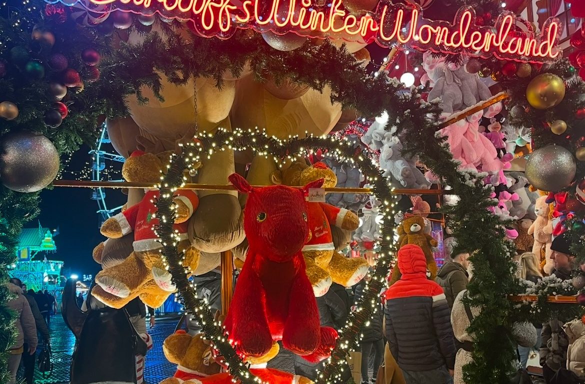 Winter Wonderland Sign with stalls and lights in the background with a Welsh Dragon teddy in the centre