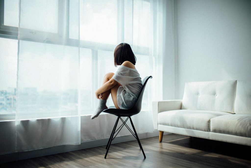 Image of a woman sitting on a chair with her knees to her chest.