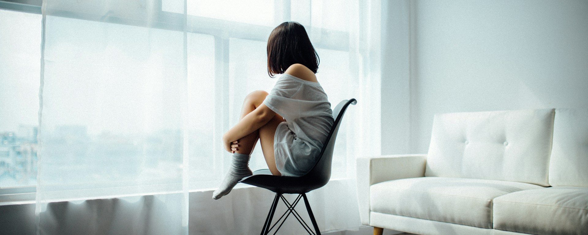 Image of a woman sitting on a chair with her knees to her chest.