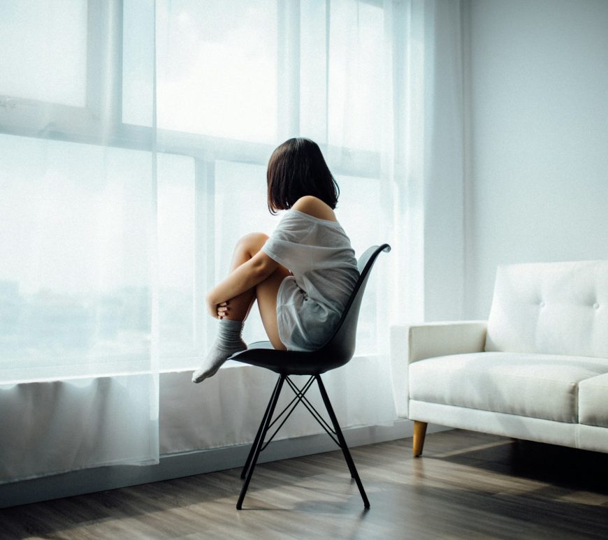 Image of a woman sitting on a chair with her knees to her chest.