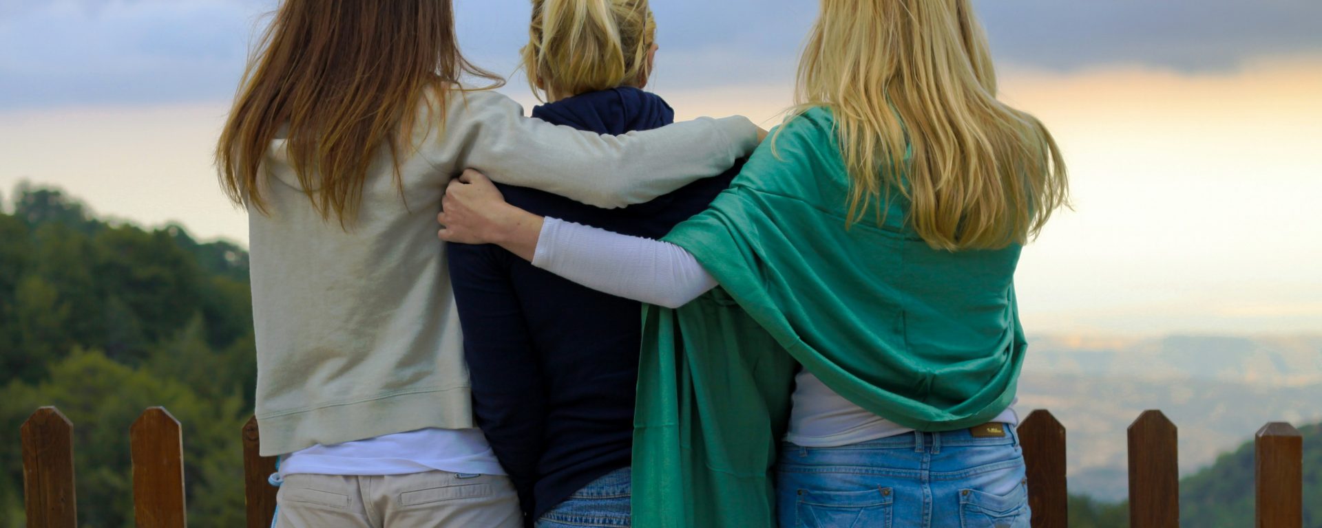 three women embracing, watching the sunset