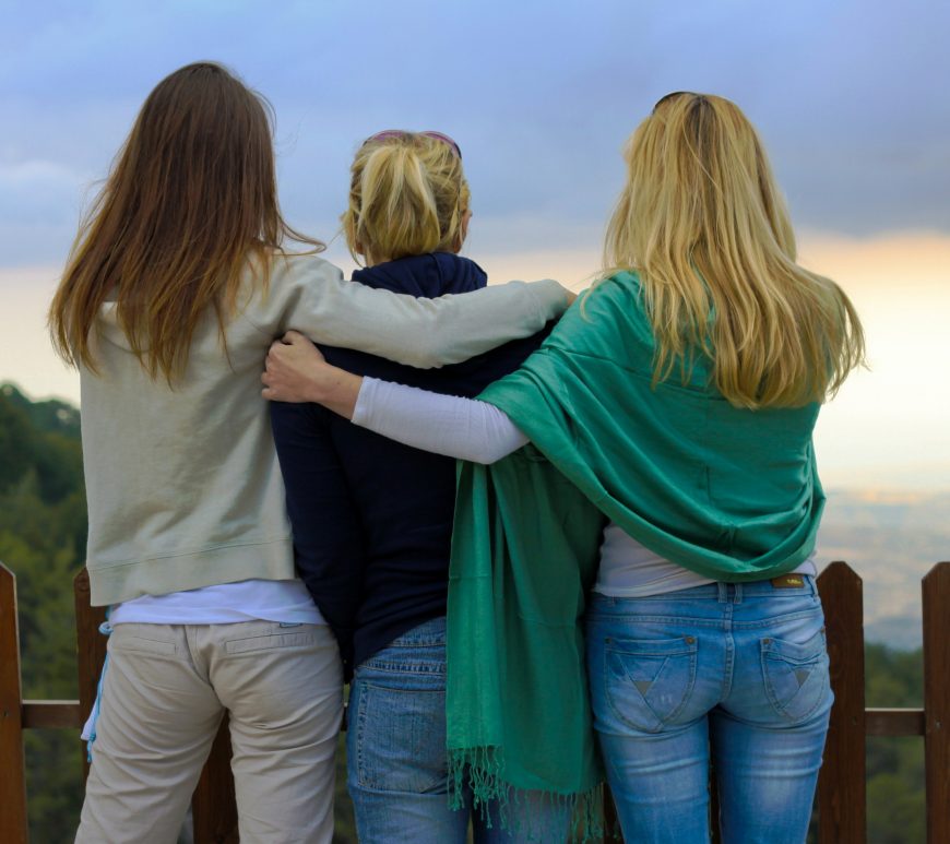 three women embracing, watching the sunset