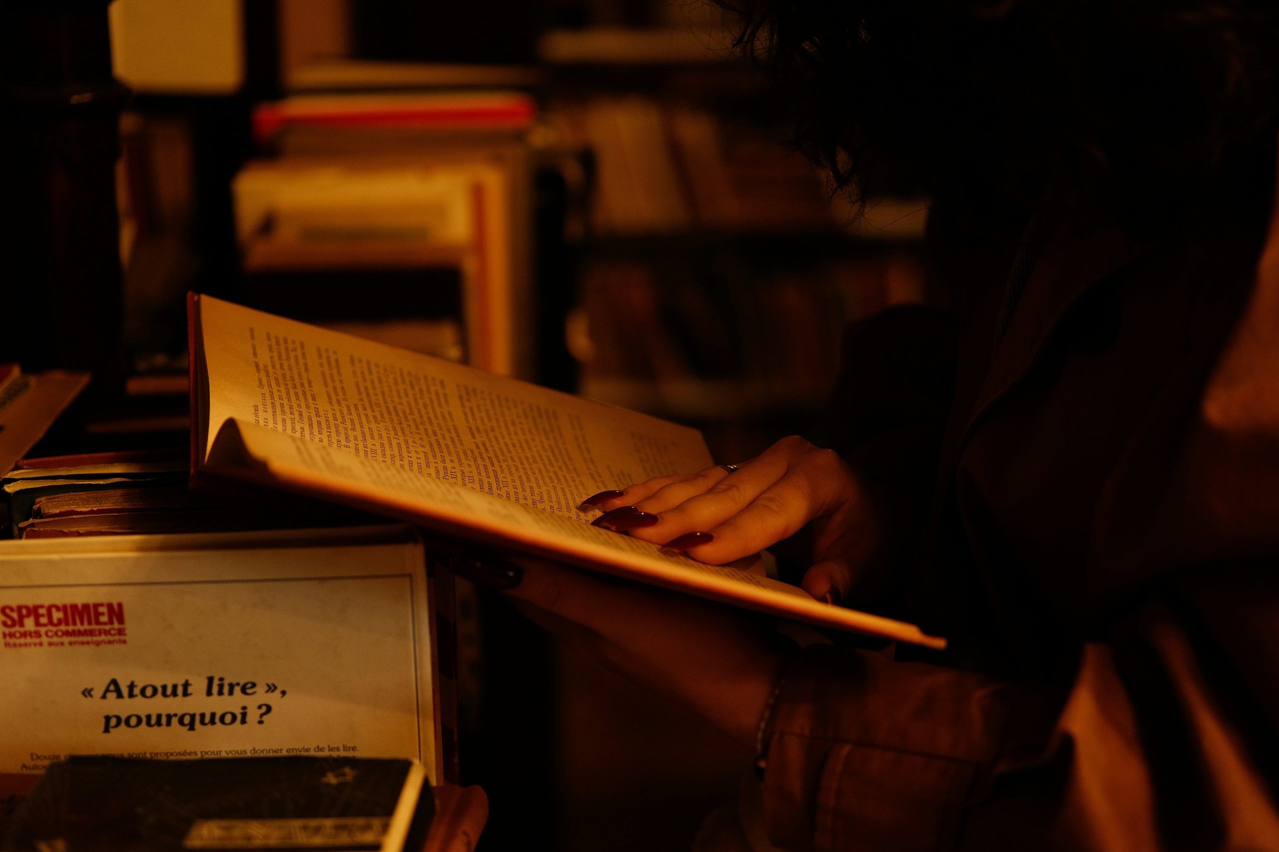 Person flicking though book in dimly-lit bookstore