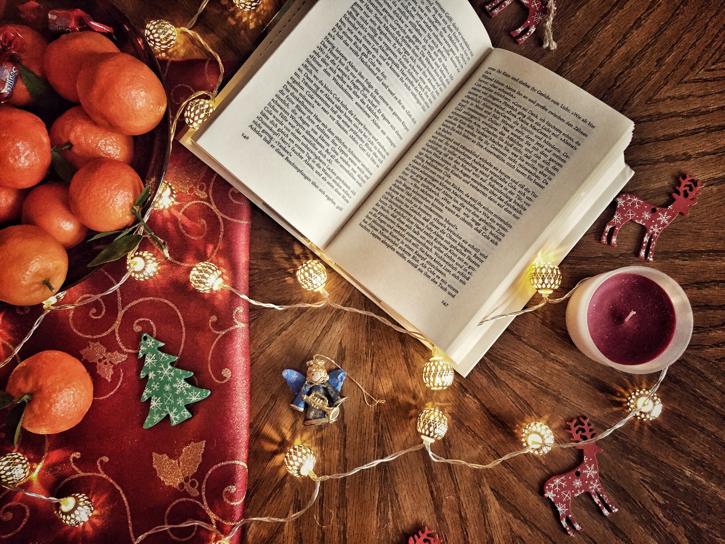 book on table covered in festive decorations and fairy lights.
