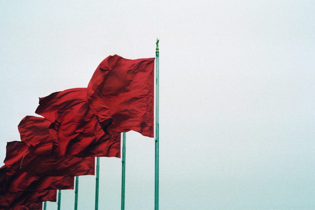Six red flags over a white background