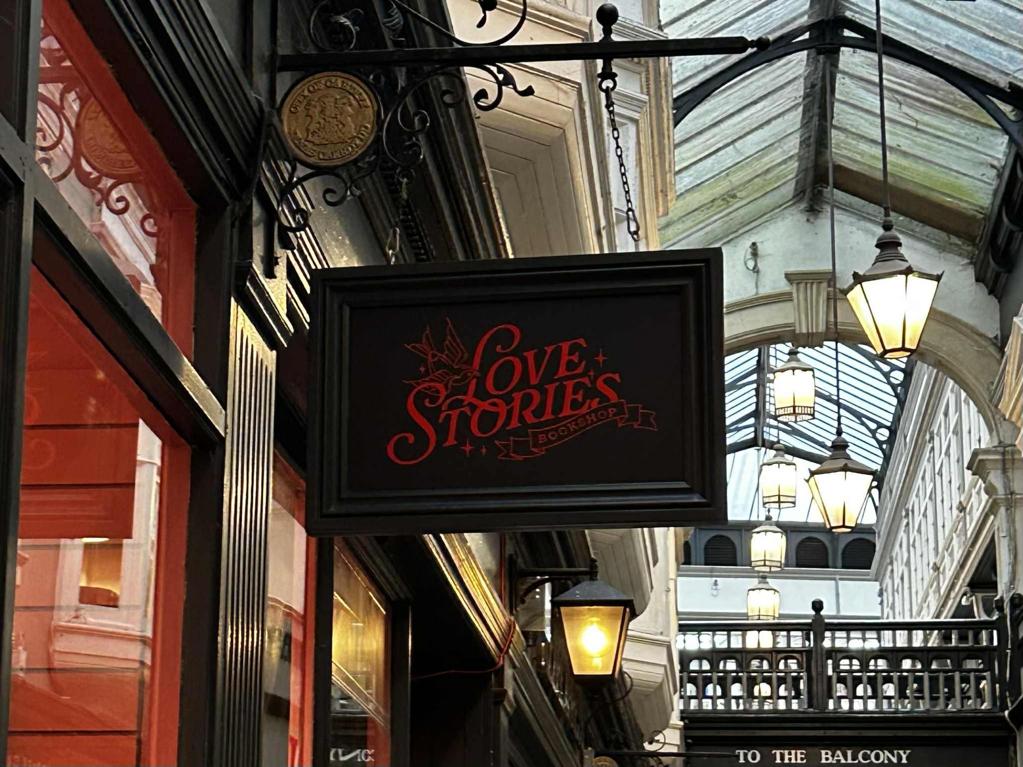 A shop sign hanging from a shop entrance with Love Stories written on it