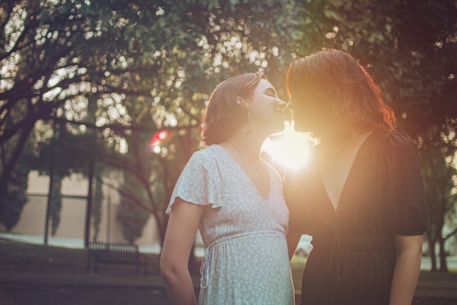 Two women kissing under some trees