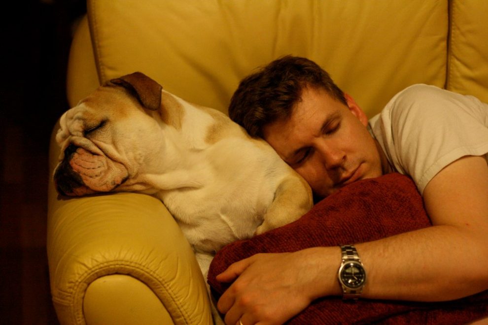 man cuddling dog on sofa